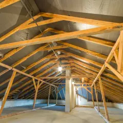 Charpente en bois d'un grenier en cours d'aménagement, avec une bâche noire recouvrant la structure de la r toiture.