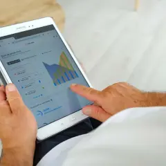 Un homme consulte sur sa tablette le suivi de sa production solaire EDF ENR, vérifiant le délai signature contrat EDF OA.