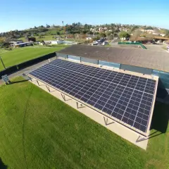 Panneaux solaires sur un bâtiment, assurant une rentabilité 100 kw photovoltaïque. Le paysage environnant est verdoyant.