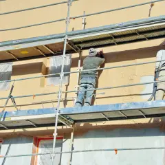 Travaux d'enduisage sur échafaudage. Le prix pour enduire un mur extérieur dépend de la technique et des matériaux.