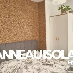 Chambre avec mur en panneau isolant en liège texturé. Un lit et une armoire complètent la pièce.
