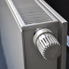 Gros plan sur un radiateur blanc, élément clé d'une installation de chauffage central, avec sa molette de réglage de température.
