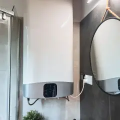 Chauffe-eau électrique instantané : les inconvénients de son installation dans une petite salle de bain. Miroir rond suspendu.