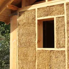 Construction d'une maison en paille, aperçu d'un mur avec fenêtre. Le prix d'une maison paille 100m2 est une question d'actualité.