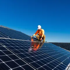 Un technicien installe des panneaux solaires sur un toit, une étape clé pour l'autoconsommation sans déclaration Enedis.