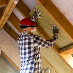 Un ouvrier installe un isolant, un correcteur thermique essentiel, dans les combles aménagés.
