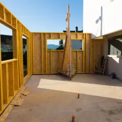 Chantier d'une extension bois, murs en ossature jaune et panneaux OSB, avec vue sur le paysage.