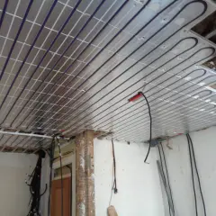 Panneaux de plafond rayonnant installés, prêts pour une chaleur douce et uniforme. Des câbles électriques sont visibles, en attente de connexion.