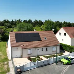 Maison avec panneaux photovoltaïques en vente, un véhicule vert et blanc garé devant.