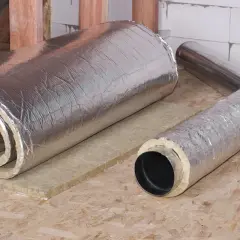 Rouleau d'isolant thermique et conduit de ventilation gainé, prêts pour une isolation multicouche efficace.