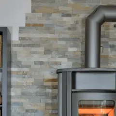 Poêle moderne avec mur en pierre. Le tubage de cheminée est visible. Le prix du tubage de cheminée est une préoccupation pour les propriétaires.