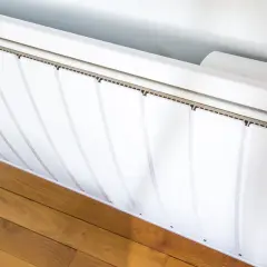 Radiateurs basse consommation blancs, modernes, avec un écran digital affichant la température. Ils sont installés sur un parquet en bois.