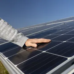 Main posée sur des panneaux photovoltaïques, vérifiant la température sous le soleil.