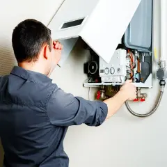 Un technicien vérifie le bon fonctionnement d'une chaudière pulsatoire murale, s'assurant que tout est en ordre pour un chauffage optimal.