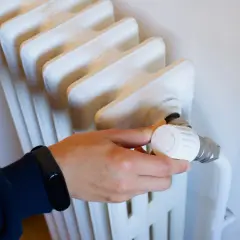 Main tenant ajuste le thermostat d'un radiateur qui fait du bruit, espérant trouver le silence.