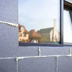 Mousse isolante appliquée sur des blocs de béton pour un enduit isolant extérieur. Reflets de maisons dans la fenêtre.