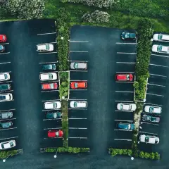 Vue aérienne d'un parking avec des voitures garées. La loi aper est respectée, avec des places bien délimitées et des espaces verts.