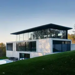 Une maison positive aux lignes épurées, avec une piscine et une vue sur la forêt.