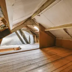 Espace brut sous les toits, idéal pour un projet de comment aménager des combles. Planchers en bois, poutres apparentes et murs en briques.