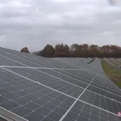 Vaste étendue de panneaux solaires sous un ciel couvert, témoignant d'un projet photovoltaïque en Nouvelle-Aquitaine.