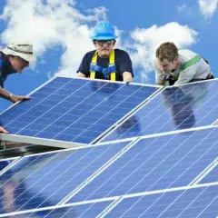 Trois techniciens installent des panneaux solaires sur un toit. Une installation sûre et pérenne, gage d'une **assurance décennale photovoltaïque** fiable.
