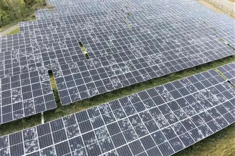 Champ de panneaux solaires recouverts de grêle, montrant la résilience de l'énergie renouvelable face aux intempéries.