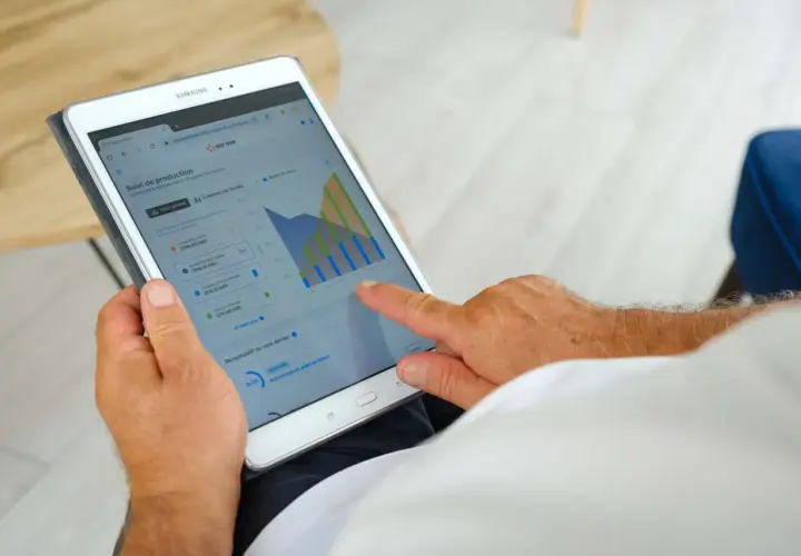 Un homme consulte sur sa tablette le suivi de sa production solaire EDF ENR, vérifiant le délai signature contrat EDF OA.
