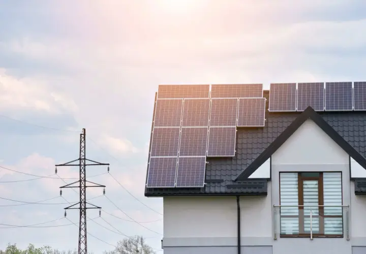 Le calepinage panneau solaire sur le toit d'une maison moderne, avec un pylône électrique en arrière-plan.