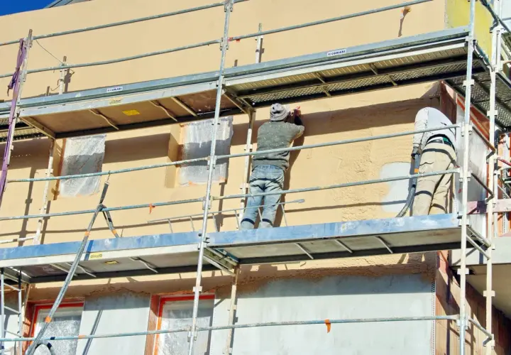 Travaux d'enduisage sur échafaudage. Le prix pour enduire un mur extérieur dépend de la technique et des matériaux.