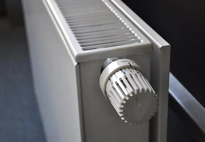 Gros plan sur un radiateur blanc, élément clé d'une installation de chauffage central, avec sa molette de réglage de température.