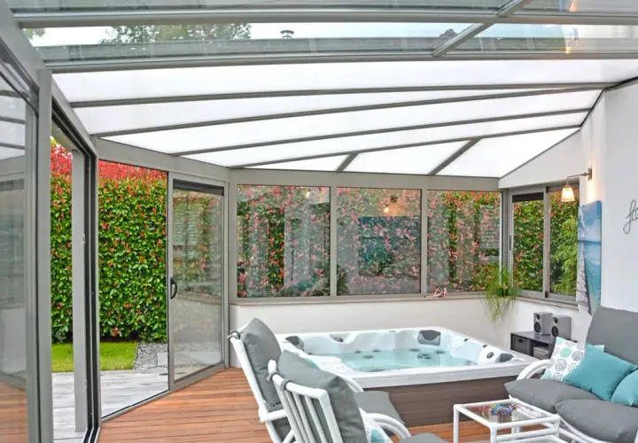 Veranda avec jacuzzi et salon, profitant d'une isolation toiture veranda par l'interieur pour un confort optimal toute l'année.