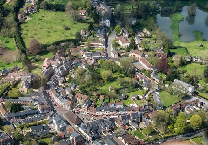 Vue aérienne d'un village pittoresque, un schéma directeur immobilier exemple, avec ses maisons aux toits de tuiles, ses rues sinueuses et son étang.