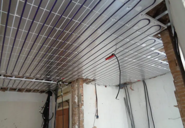 Panneaux de plafond rayonnant installés, prêts pour une chaleur douce et uniforme. Des câbles électriques sont visibles, en attente de connexion.