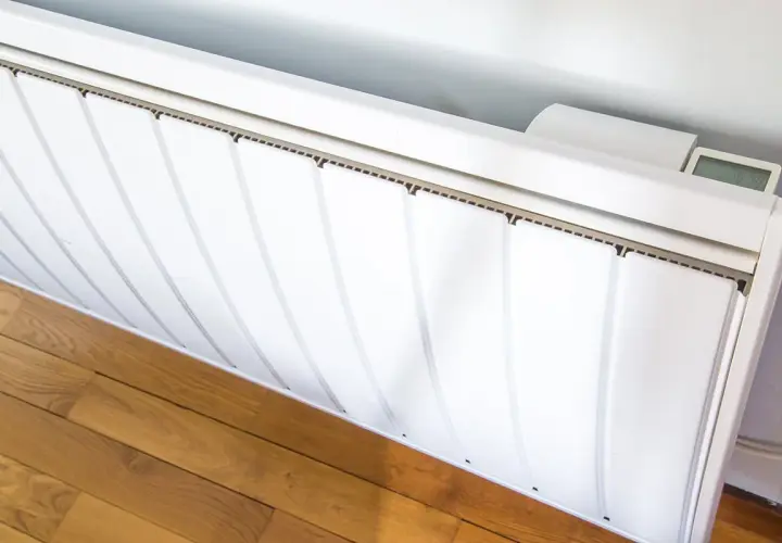 Radiateurs basse consommation blancs, modernes, avec un écran digital affichant la température. Ils sont installés sur un parquet en bois.
