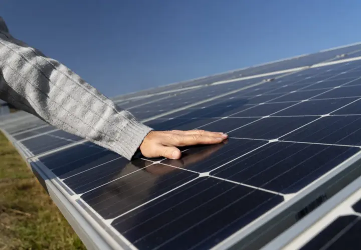 Main posée sur des panneaux photovoltaïques, vérifiant la température sous le soleil.