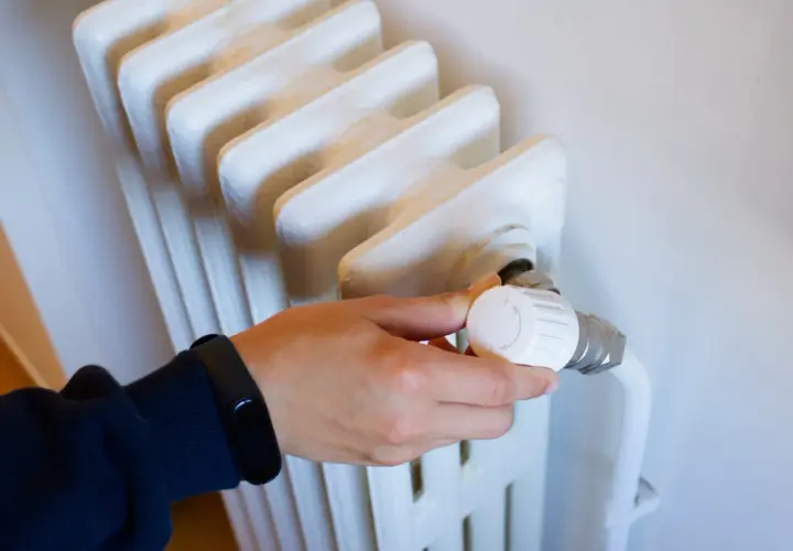 Main tenant ajuste le thermostat d'un radiateur qui fait du bruit, espérant trouver le silence.