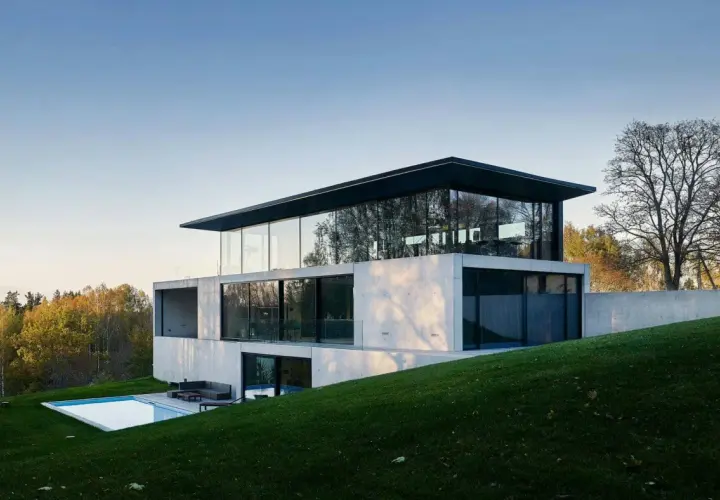 Une maison positive aux lignes épurées, avec une piscine et une vue sur la forêt.