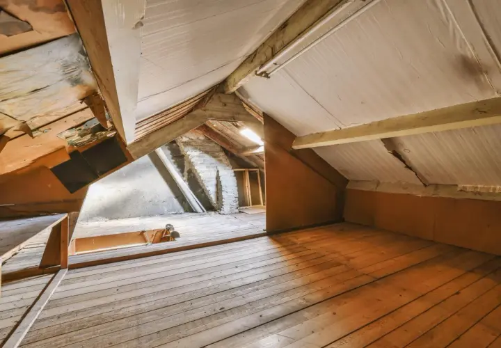 Espace brut sous les toits, idéal pour un projet de comment aménager des combles. Planchers en bois, poutres apparentes et murs en briques.