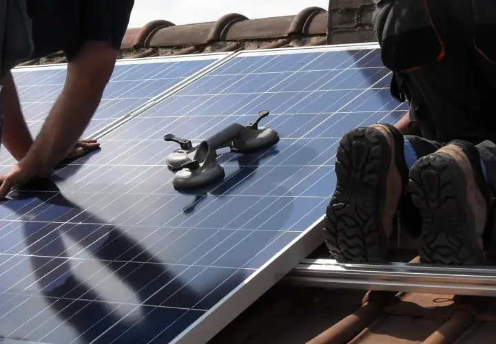 Un installateur panneau solaire agréé manipule un panneau sur un toit. Des ventouses sont prêtes à aider.