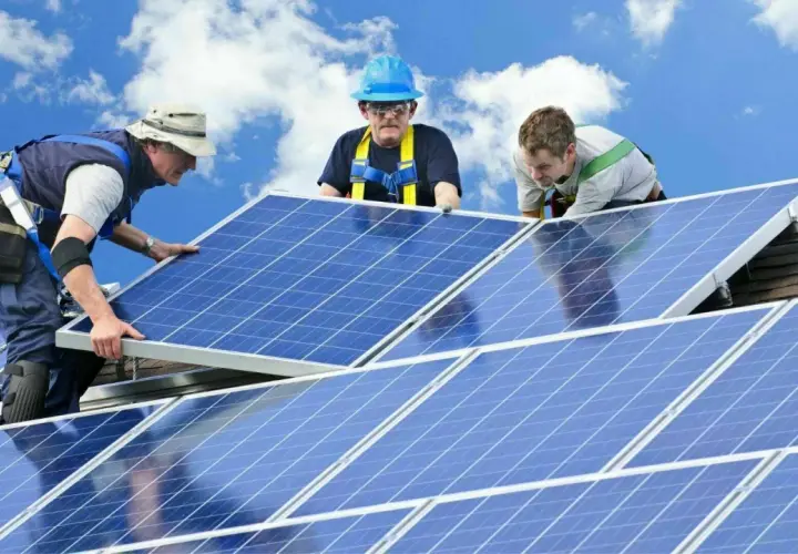 Trois techniciens installent des panneaux solaires sur un toit. Une installation sûre et pérenne, gage d'une **assurance décennale photovoltaïque** fiable.
