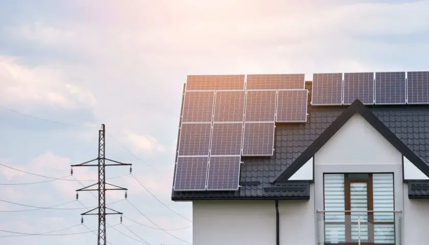 Le calepinage panneau solaire sur le toit d'une maison moderne, avec un pylône électrique en arrière-plan.