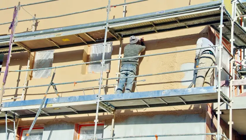 Travaux d'enduisage sur échafaudage. Le prix pour enduire un mur extérieur dépend de la technique et des matériaux.
