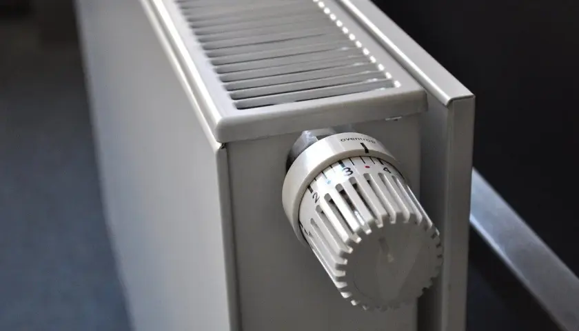 Gros plan sur un radiateur blanc, élément clé d'une installation de chauffage central, avec sa molette de réglage de température.