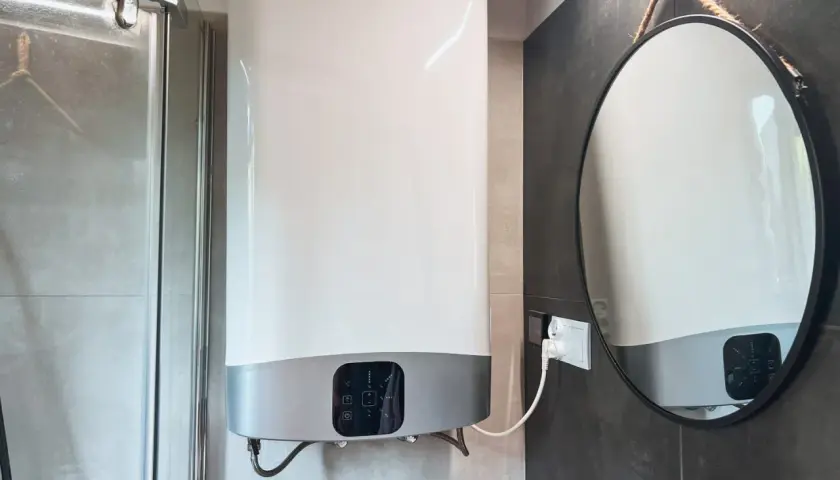 Chauffe-eau électrique instantané : les inconvénients de son installation dans une petite salle de bain. Miroir rond suspendu.