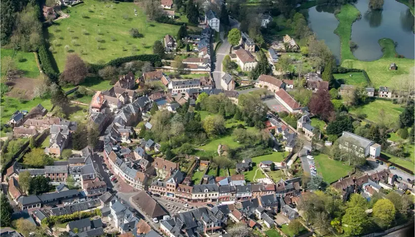Vue aérienne d'un village pittoresque, un schéma directeur immobilier exemple, avec ses maisons aux toits de tuiles, ses rues sinueuses et son étang.
