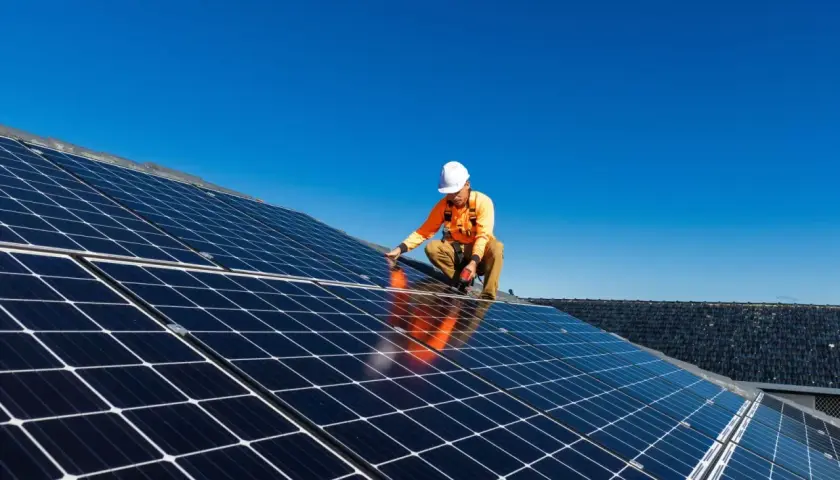Un technicien installe des panneaux solaires sur un toit, une étape clé pour l'autoconsommation sans déclaration Enedis.