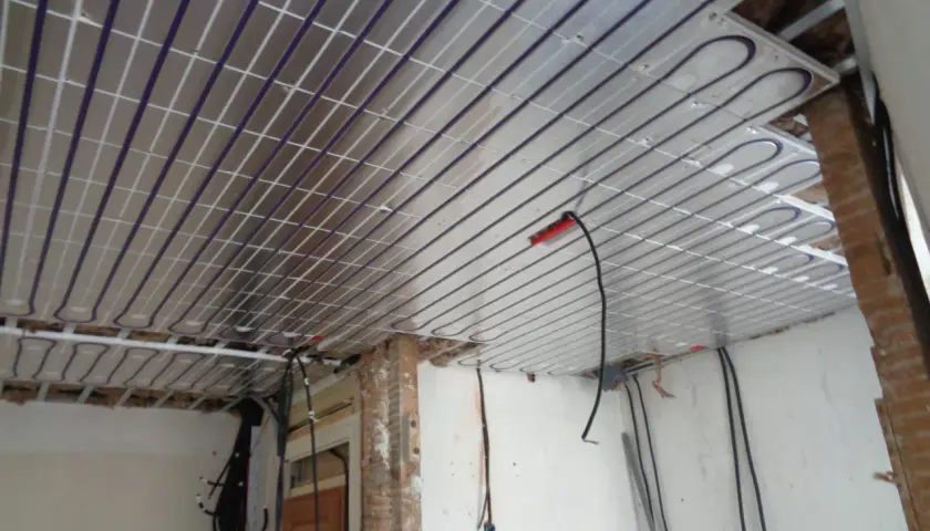 Panneaux de plafond rayonnant installés, prêts pour une chaleur douce et uniforme. Des câbles électriques sont visibles, en attente de connexion.