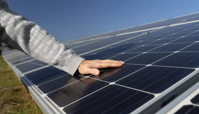 Main posée sur des panneaux photovoltaïques, vérifiant la température sous le soleil.