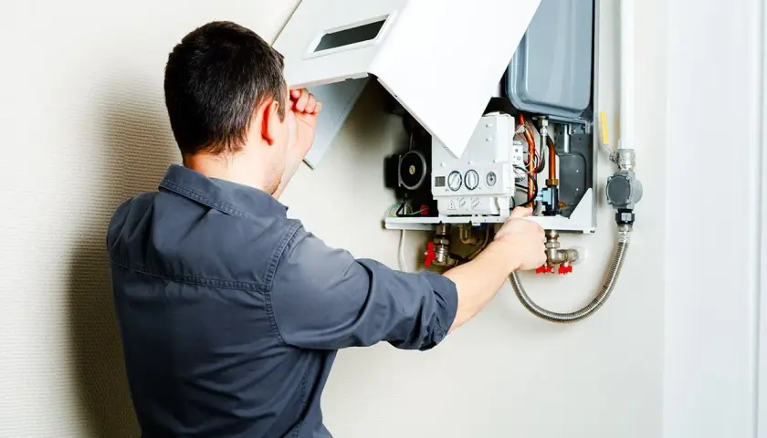 Un technicien vérifie le bon fonctionnement d'une chaudière pulsatoire murale, s'assurant que tout est en ordre pour un chauffage optimal.