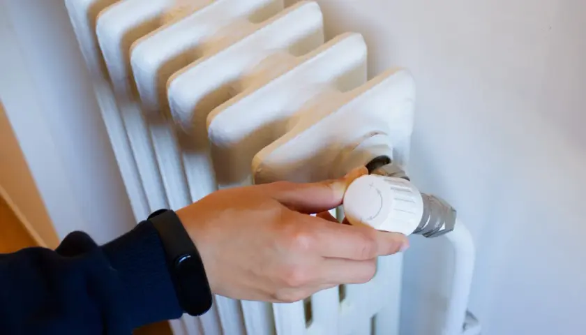 Main tenant ajuste le thermostat d'un radiateur qui fait du bruit, espérant trouver le silence.